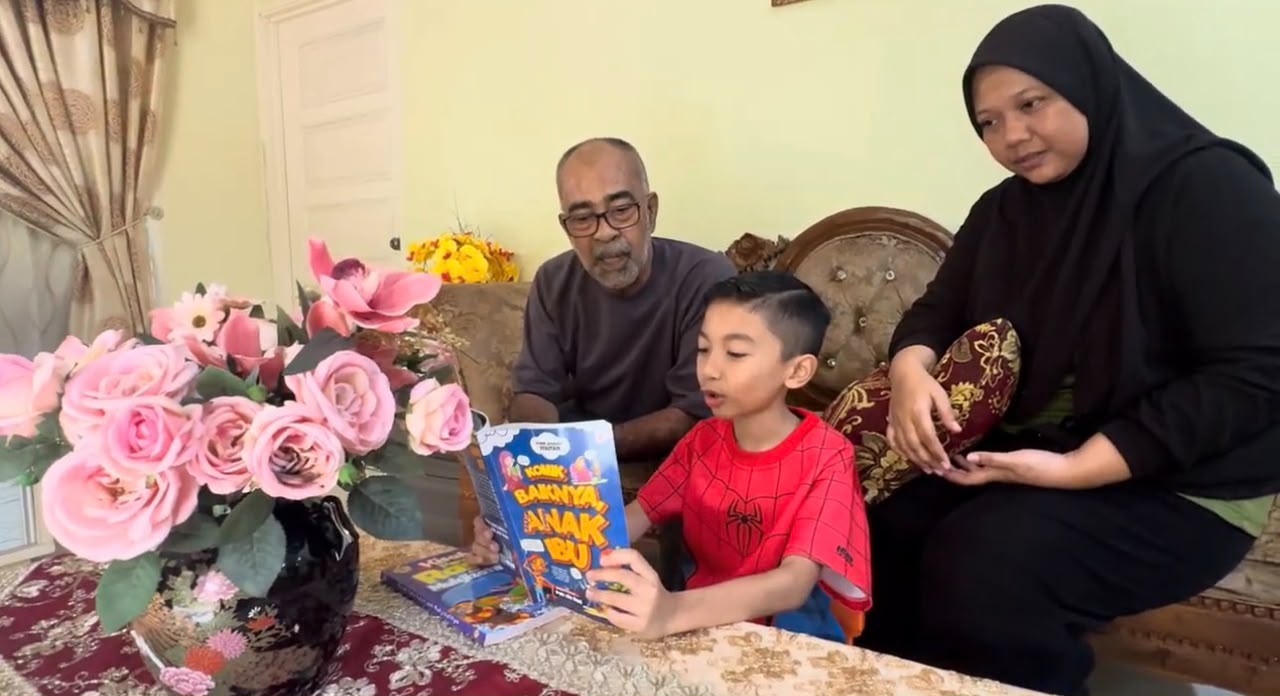 Bapa dan ibu bersama anak lelaki membaca buku cerita